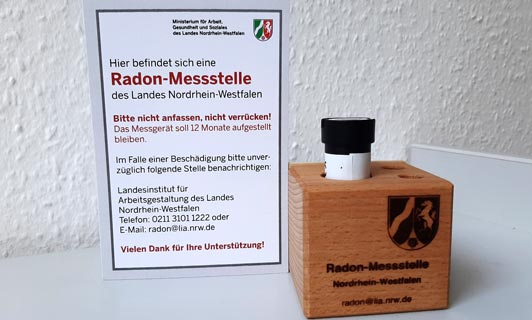  Ein passives Radon-Exposimeter in einem Aufsteller mit demLogo der Zentralen Radonstelle. Im Hintergrund der Hinweis, dass es sich um eine Radonmesstelle handelt.